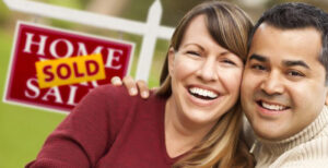 Couple in front of a sold sign